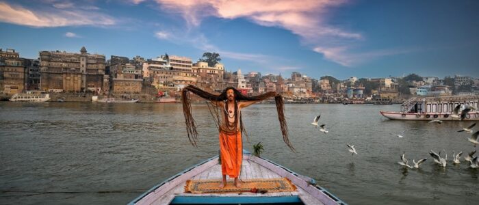 Assi-Ghat-at-sunrise-bathed-in-golden-light-with-sadhus-and-devotees-and-boats-varanasi